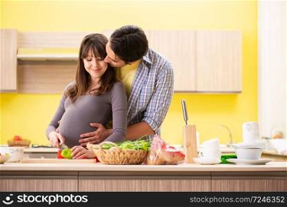 Man and pregnant woman preparing salad in kitchen 