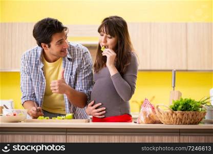 Man and pregnant woman preparing salad in kitchen . The man and pregnant woman preparing salad in kitchen 