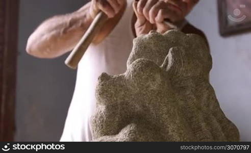 Man and profession, people and job, hispanic artisan at work in his atelier, working with stone and sculpting statue in workshop