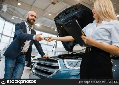 Man and salesgirl choosing auto in car dealership. Customer and seller in vehicle showroom, male person buying transport, automobile dealer business. Man and salesgirl choosing auto in car dealership