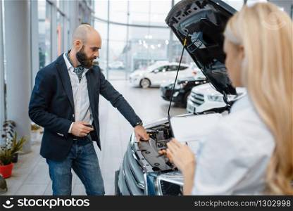 Man and saleslady choosing auto in car dealership. Customer and seller in vehicle showroom, male person buying transport, automobile dealer business. Man and saleslady choosing auto in car dealership