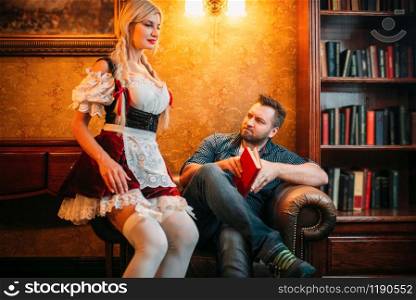 Man and sexy waitress in traditional retro style dress in pub, oktoberfest holidays. Male person and seductive barmaid with with attractive shapes in bar