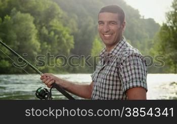Man and sport, mid adult fisherman on holiday on river, relaxing and fishing trout, smiling and looking at camera. Part 7 of 8