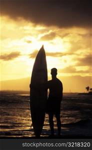 Man and Surfboard at Sunset