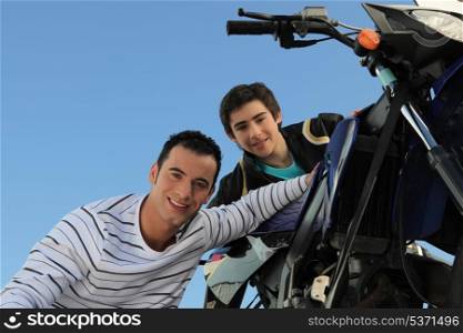 man and teenager watching motorbike