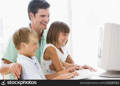Man and two young children in home office with computer smiling
