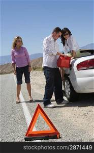 Man and two young women refuelling car on road