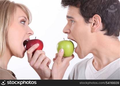 Man and woman about to bite into apples