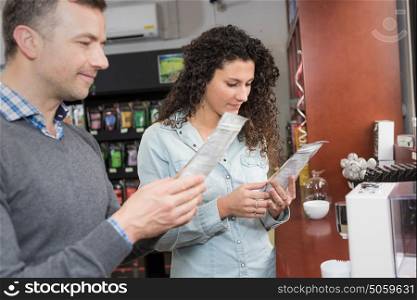 Man and woman by vending machine reading packet