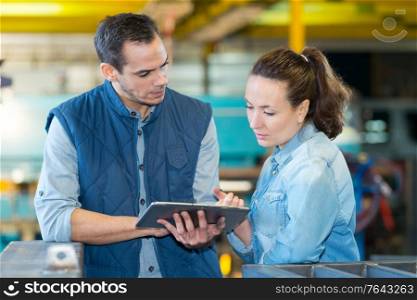 man and woman checking a tablet in factory