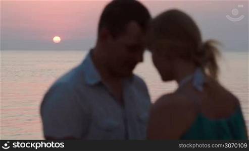 Man and woman coming close to each other against sunset over sea. Love and romantic moments