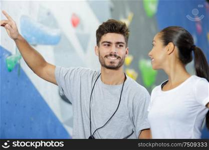 man and woman discussing about climbing wall in gym