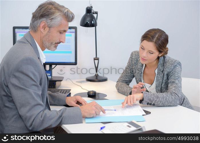 Man and woman discussing paperwork in office