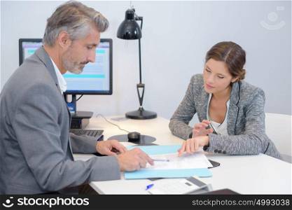 Man and woman discussing paperwork in office