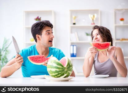 Man and woman eating watermelon at home