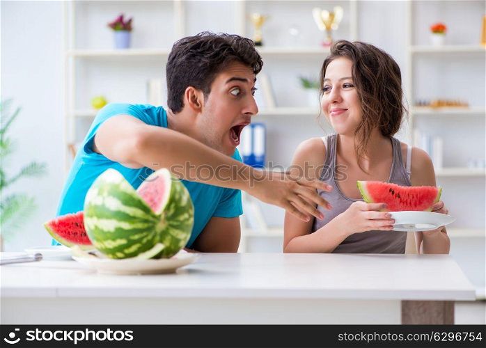 Man and woman eating watermelon at home