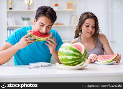 Man and woman eating watermelon at home