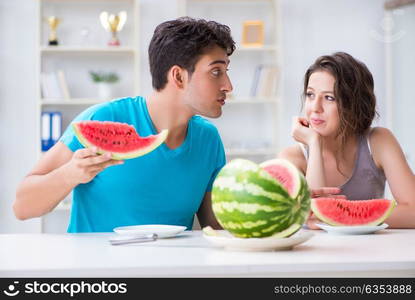 Man and woman eating watermelon at home