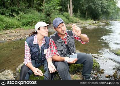 Man and woman fly fishing in river