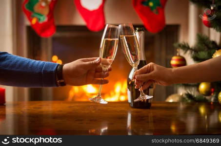 Man and woman having Christmas dinner and clinking glasses next to burning fireplace