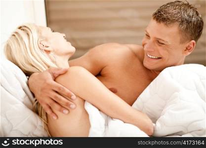 Man and woman having fun in bed and smiling