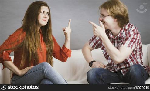 Man and woman having horrible fight while sitting on sofa. Friendship, couple breakup difficulties and problems concept.. Man and woman having fight