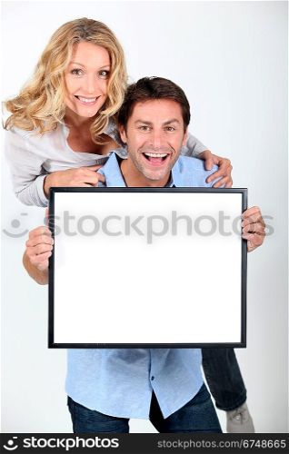 Man and woman holding up a blank poster