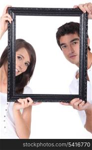 Man and woman holding up a picture frame