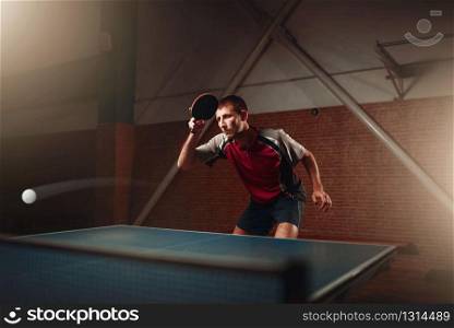 Man and woman holds ping pong rackets indoors. Couple in sportswear plays table tennis in gym. Male and female persons in table-tennis club