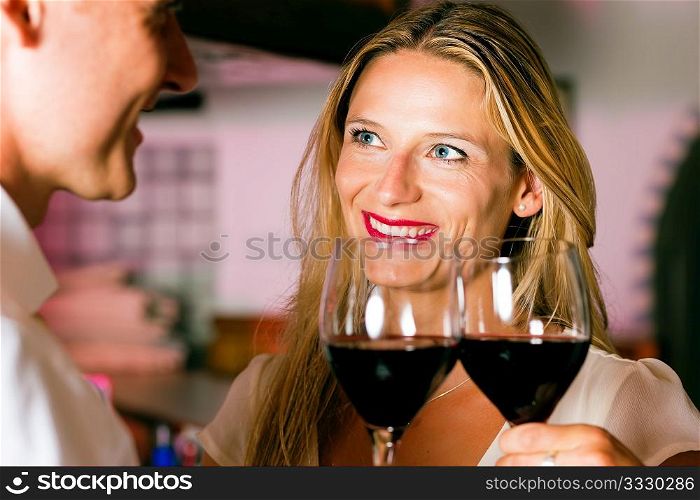 Man and woman in a hotel bar in the evening having glasses of red wine and a little flirt