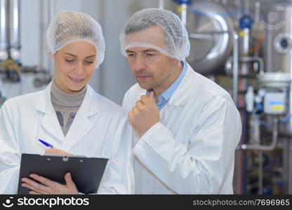 man and woman in lab coats working in a factory