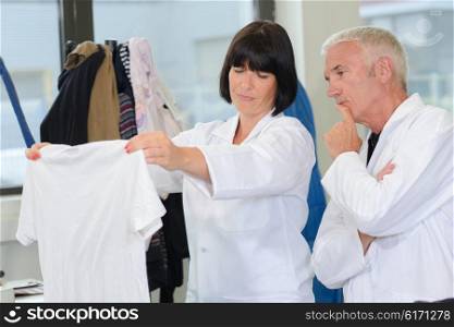 Man and woman in laundrette looking at T-shirt