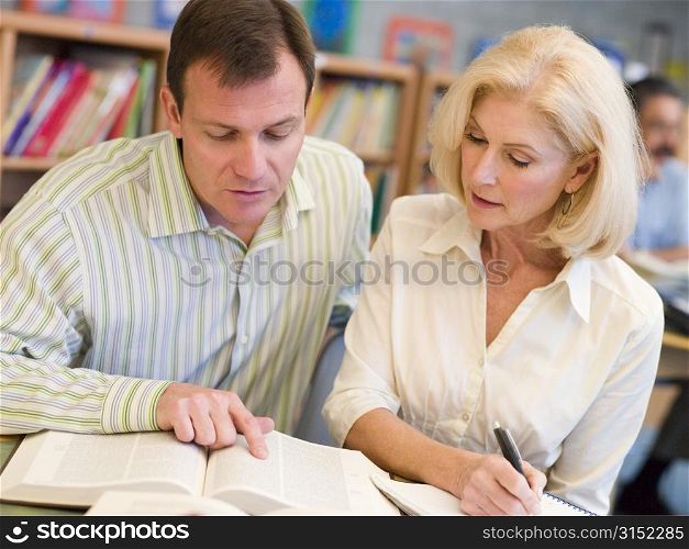 Man and woman in library looking over a book (selective focus)