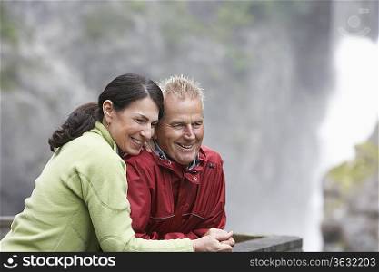 Man and woman in mountains, looking down, smiling