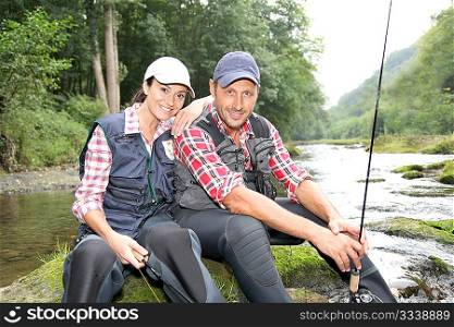 Man and woman in river fly fishing