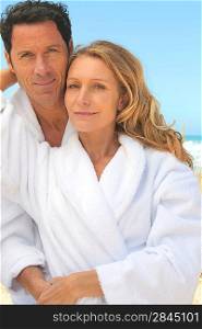 Man and woman in toweling robes on the beach