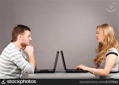 man and woman is sitting together on gray background with laptop