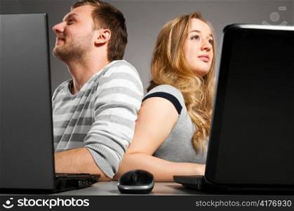 man and woman is sitting together on gray background with laptop