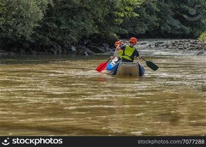 Man and woman kayaking on a river. Outdoor sport. Real people.