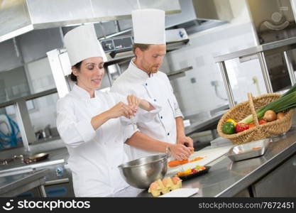 man and woman kitcheners in uniform are cutting vegetables