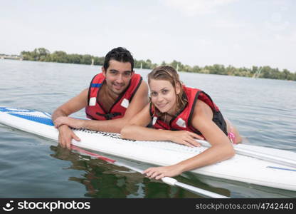 Man and woman laying on surfboard in the water