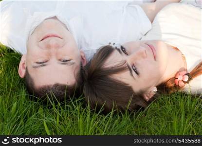 Man and woman lie on the grass and look up. Outdoor portrait