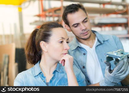 man and woman looking at metal component