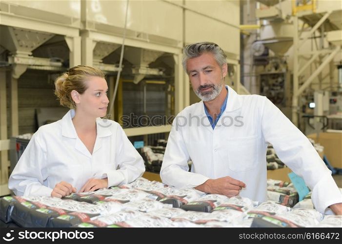 Man and woman looking at packages in factory