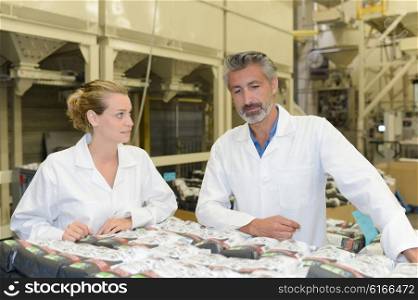 Man and woman looking at packages in factory