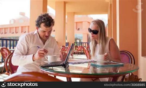 Man and woman meeting on business to sign documents on a cafe terrace