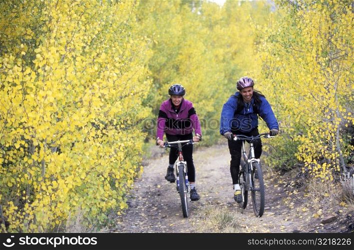 Man and Woman Mountain Biking Through Aspens