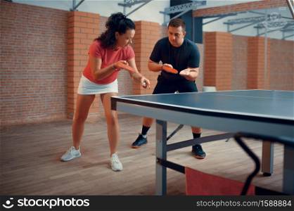 Man and woman on table tennis training, ping pong players. Couple playing table-tennis indoors, sport game with racket and ball, active healthy lifestyle. Man and woman on table tennis training, ping pong