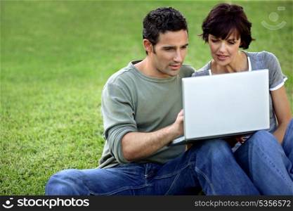 Man and woman on the grass with laptop