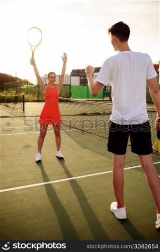 Man and woman play tennis, training on outdoor court. Active healthy lifestyle, people play sport game, fitness workout with racquets. Man and woman play tennis on outdoor court